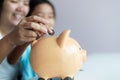 Mother and daughter putting coin into the piggy bank for money saving for the future concept select focus shallow depth of field Royalty Free Stock Photo