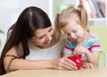 Mother and daughter putting coins into piggy bank