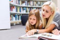 Mother with daughter read book together in library