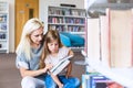 Mother with daughter read book together in library Royalty Free Stock Photo