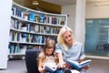 Mother with daughter read book together in library Royalty Free Stock Photo