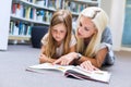 Mother with daughter read book together in library Royalty Free Stock Photo