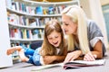 Mother with daughter read book together in library Royalty Free Stock Photo