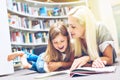 Mother with daughter read book together in library Royalty Free Stock Photo