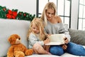 Mother and daughter reading book sitting by christmas decor at home Royalty Free Stock Photo