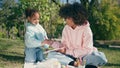 Mother daughter relaxing picnic at sunny meadow close up. Girl painting paper Royalty Free Stock Photo