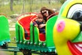 Mother and daughter riding a caterpillar carousel train in the spring public park