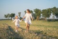 A mother and daughter run into the field by the hand. Happy childhood with my mother. Daughter and mother in a white Royalty Free Stock Photo