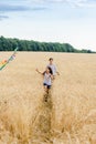 Mother and daughter run in a wheat field with a kite in the summer. Well-planned and active weekend. Happy childhood. Royalty Free Stock Photo