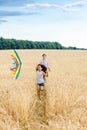 Mother and daughter run in a wheat field with a kite in the summer. Well-planned and active weekend. Happy childhood. Royalty Free Stock Photo