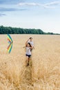 Mother and daughter run in a wheat field with a kite in the summer. Well-planned and active weekend. Happy childhood. Royalty Free Stock Photo