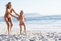 Mother And Daughter Running Along Beach Together Wearing Swimming Costume Royalty Free Stock Photo