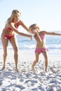 Mother And Daughter Running Along Beach Together Wearing Swimming Costume Royalty Free Stock Photo