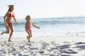 Mother And Daughter Running Along Beach Together Wearing Swimming Costume Royalty Free Stock Photo