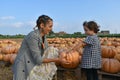 a mother and daughter sharing some pumpkins in an orchard