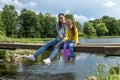 A mother and daughter sit on a bridge across a river on a  summer day Royalty Free Stock Photo