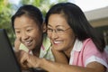 Mother and Daughter sitting at backyard table Using Laptop Together close up Royalty Free Stock Photo