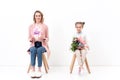 mother and daughter sitting on chairs and looking at camera on happy