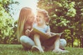 Mother and daughter sitting on green grass and reading book together. Little girl sitting on mother lap. Royalty Free Stock Photo