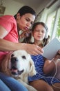 Mother and daughter sitting with pet dog and using digital Royalty Free Stock Photo