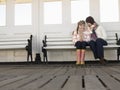 Mother And Daughter Sitting On Pier Bench