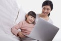 Mother and daughter sitting on sofa using a laptop, tilt Royalty Free Stock Photo