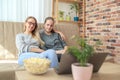 Mother with daughter sitting on sofa and watching series