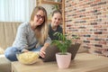 Mother with daughter sitting on sofa and watching series