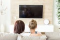 Mother and daughter sitting on sofa and watching tv, single mother concept, back view Royalty Free Stock Photo