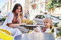 Mother and daughter sitting in street cafe summer time happy family day beautiful cute woman and small little girl in restaurant Royalty Free Stock Photo