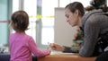 Mother and daughter sitting in waiting hall at airport with exercise book