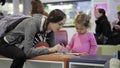 Mother and daughter sitting in waiting hall at airport with exercise book