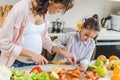 mother with daughter slicing carrots on chopping board