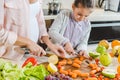 partial view of mother with daughter slicing carrots on chopping board