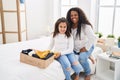 Mother and daughter smiling confident folding clothes to donate at bedroom Royalty Free Stock Photo