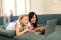 Mother and daughter smiling and having fun together playing and surfing on the internet on a laptop