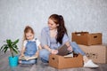 Mother and daughter sort things out after moving to a new house or apartment. A woman and a little girl sit on the floor Royalty Free Stock Photo