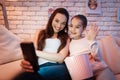 Mother and daughter speaking with father on phone at night at home. Royalty Free Stock Photo