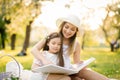 A mother and daughter in the spring garden on a plaid leaf through and look through a book with photos from a family photo shoot. Royalty Free Stock Photo