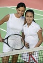 Mother and daughter standing at net on tennis court portrait high angle view