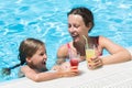 Mother and daughter swimming with drink in hand Royalty Free Stock Photo