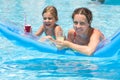 Mother and daughter swimming with a drink Royalty Free Stock Photo