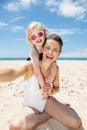 Mother and daughter in swimsuits taking selfies at beach Royalty Free Stock Photo