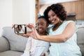 Mother and daughter tacking selfie on mobile home in living room Royalty Free Stock Photo