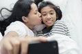 Mother and daughter are taking a picture together. Asian women and cute girl so fun and happy  selfie on the bed Royalty Free Stock Photo