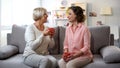 Mother and daughter talking at home, relaxing on sofa with cups of coffee, trust Royalty Free Stock Photo