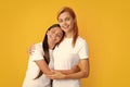 Mother and daughter teenager girl in t-shirt embrace cudding isolated on yellow color background studio. Mothers day Royalty Free Stock Photo