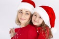 Mother and daughter together in Christmas Santa hats are waiting for the New year. Royalty Free Stock Photo