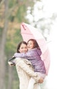 Mother and daughter under umbrella in autumn.