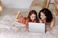Mother and daughter using laptop on bed in holiday at home. Royalty Free Stock Photo